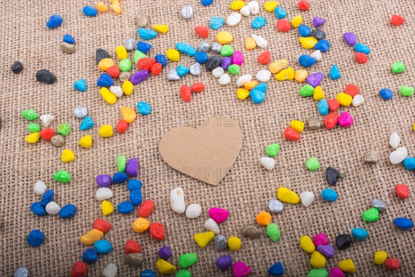 Paper heart amid colorful pebbles on canvas ground