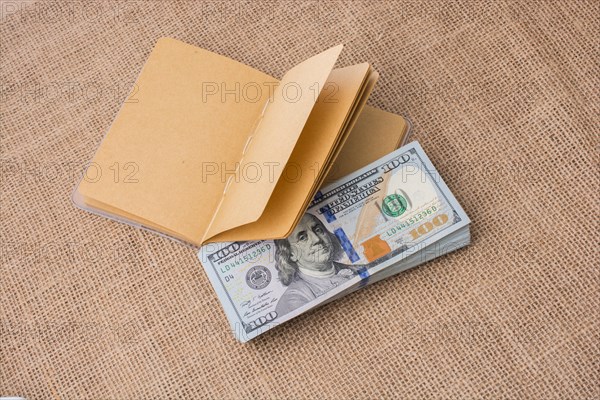 Notebook placed beside bundle of US dollar banknotes