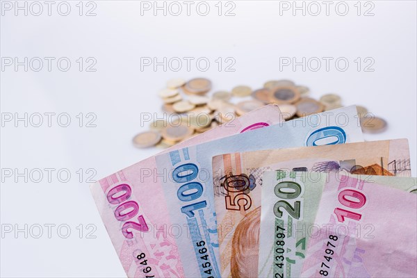 Turkish Lira coins and banknotes side by side on white background