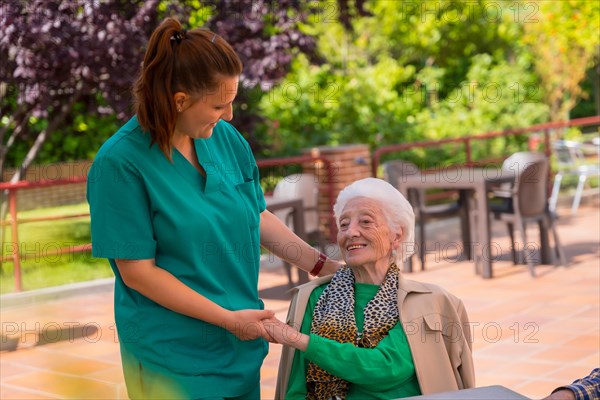 An older or mature woman with the nurse in the garden of a nursing home or retirement home