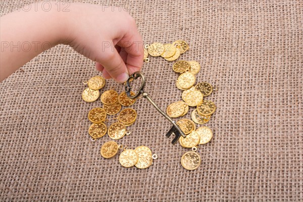 Hand holding a retro styled key over fake gold coins