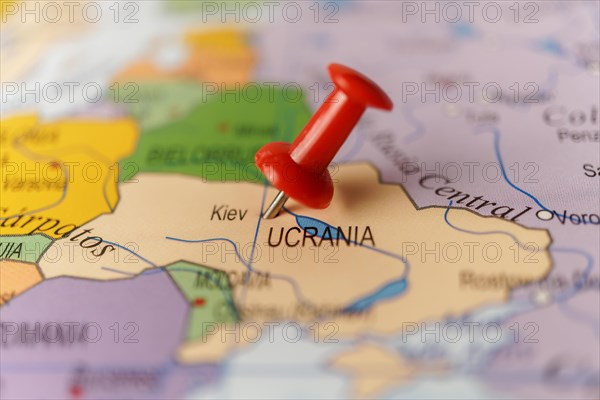 Ukraine marked with a red thumbtack on a map with an out-of-focus background
