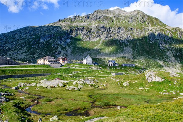 Panoramic view onto the high plateau at the top of the pass 2091 metres high Gotthard Pass with historic buildings in the middle historic hotel accommodation Ospizio San Gottardo Saint Gotthard Hospice with historic buildings from year 1237 13th century