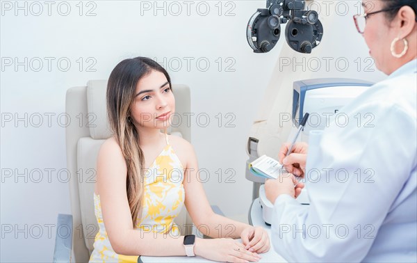 Female patient having consultation with optometrist in office. Optometrist with female patient taking notes in office