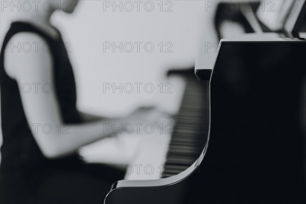 Elegant girl sits at the concert grand and plays the piano