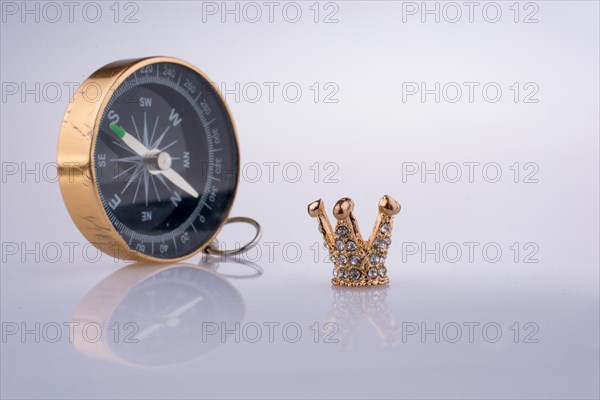 Compass and Golden color crown model with pearls on white background