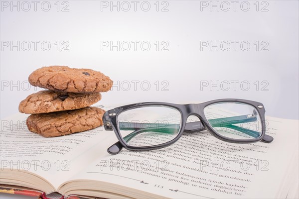 Chocolate chip cookies and glasses placed on a book