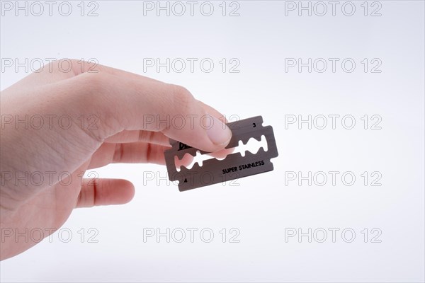 Hand holding a razor blade on a white background