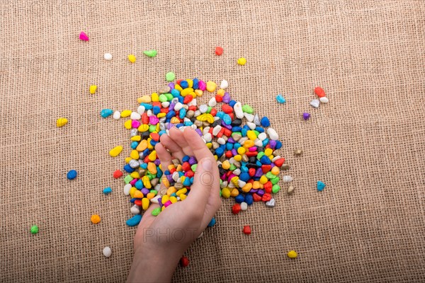 Colorful little pebbles in hand and on canvas ground