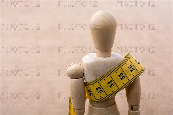 Yellow color measuring tape wrapped on wooden man