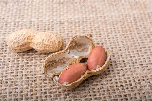 Cracked open peanuts with shell on a linen canvas background