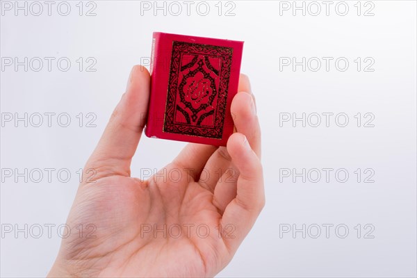 Hand holding The Holy Quran on a white background