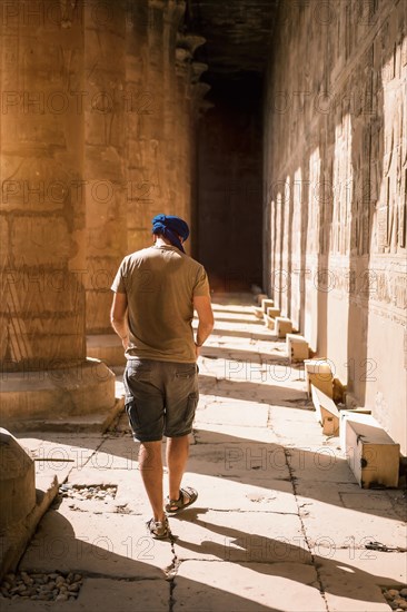 Young man in blue turban walking on the columns of the Edfu Temple near the city of Aswan. Egypt