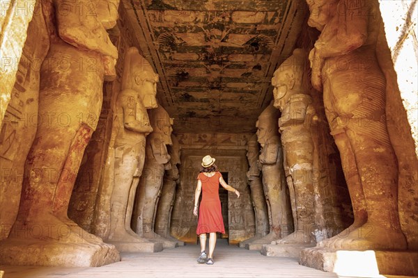 A young woman in a red dress at the Abu Simbel Temple next to the sculptures