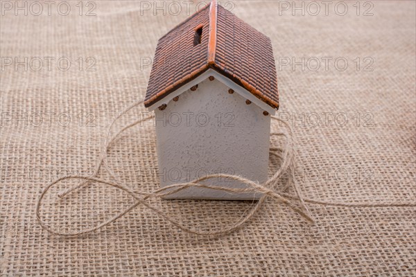 Thread wrapped around a model house on a brown background