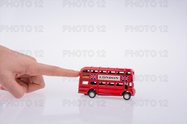 Child hand playing with London double decker bus model on white background