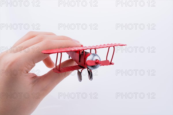 Hand holding a red toy plane on a white background