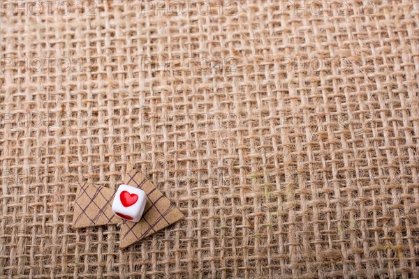 Love cubes on arrow cut out of brown paper on canvas