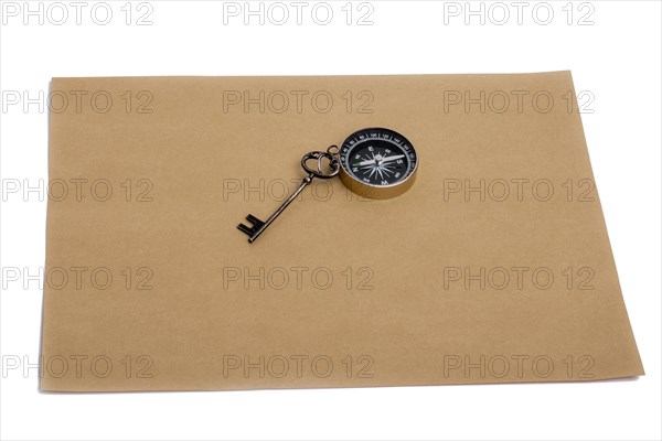 Key and compass on a sheet of colored plain paper with a white background
