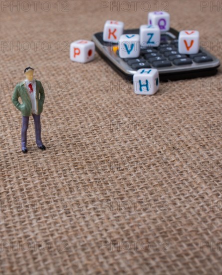 Colorful letter cubes and a calculator beside a figurine