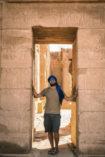 Portrait of a young man with a blue turban at the entrance to the Edfu Temple near the city of Aswan. Egypt