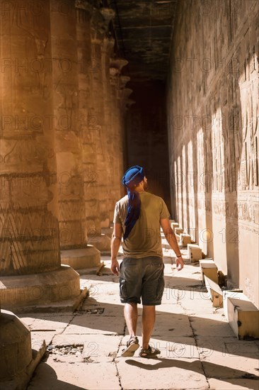 Young man in blue turban walking on the columns of the Edfu Temple near the city of Aswan. Egypt