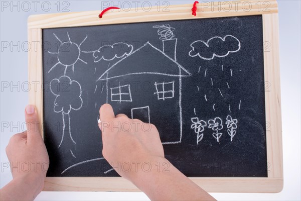 Hand drawing a house on the blackboard with a chalk