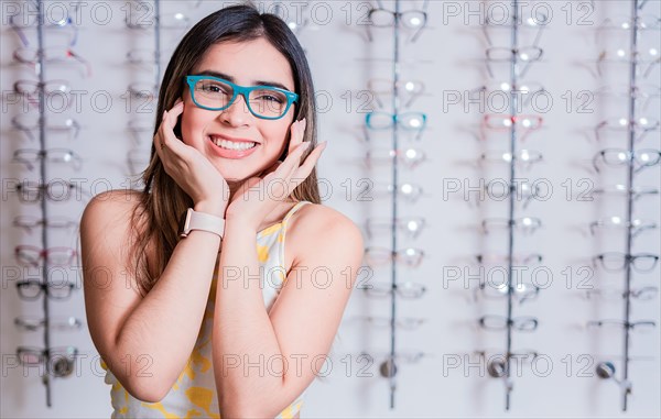 Smiling happy girl in eyeglasses with store eyeglasses background