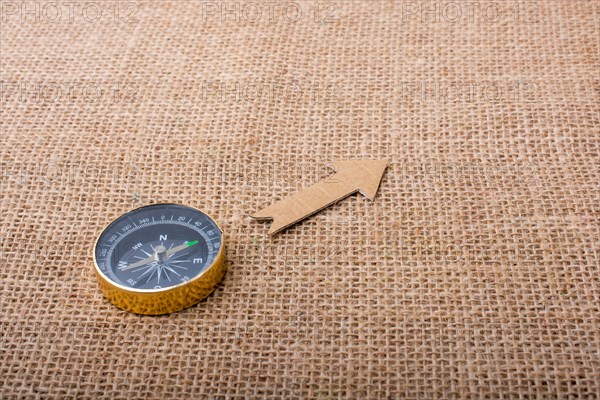 Compass and paper arrow on a canvas background