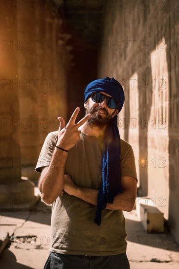 A young tourist in a blue turban visiting the Edfu Temple in the morning near Aswan city. Egypt