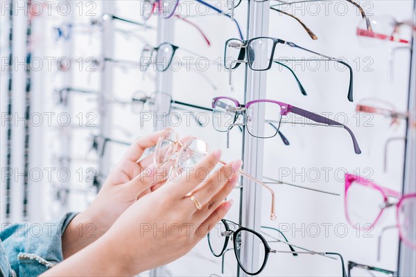 Female customer choosing glasses in an optical store. Girl hands choosing glasses in a store