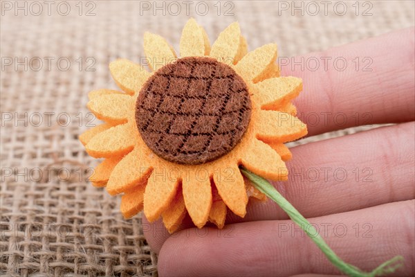 Fake flower in the hand of a child on brown background