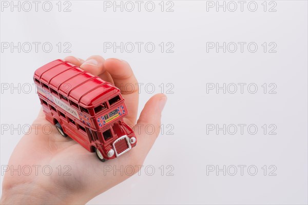 Hand holding a London double decker bus on a white background