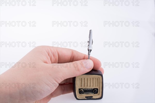 Hand holding a retro TV model on a white background