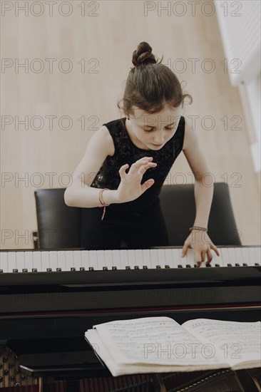 Elegant girl sits at the concert grand and plays the piano