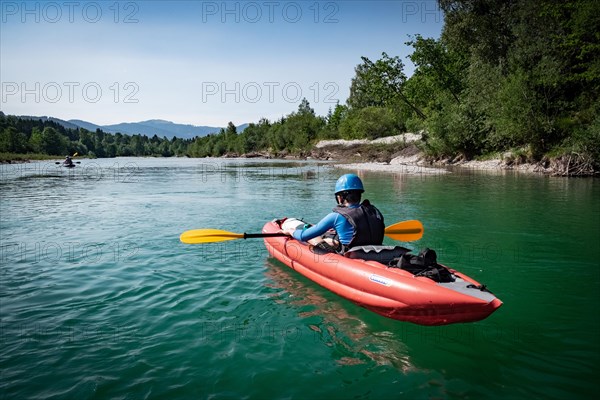 A boy paddles his kayak on a river in Upper Bavaria