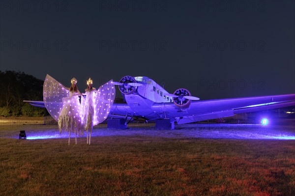 Illuminated winged creatures on stilts