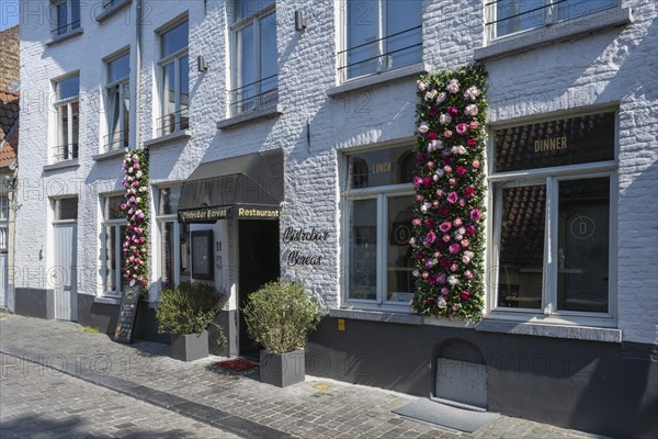 House facade decorated with flowers from a restaurant in the old town of Bruges