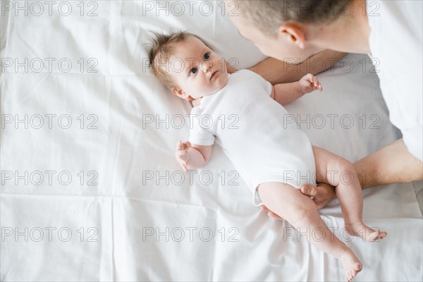 Father softly embracing baby bed