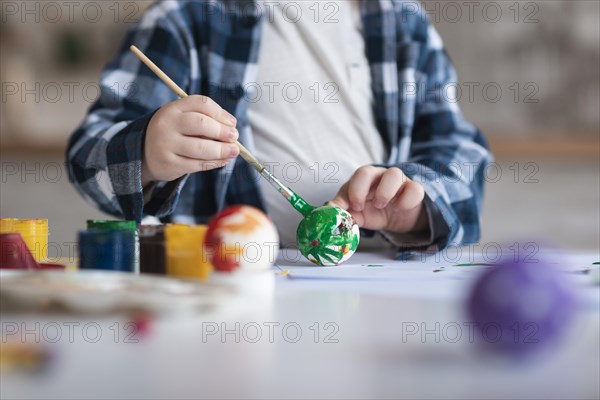 Close up little boy painting eggs easter