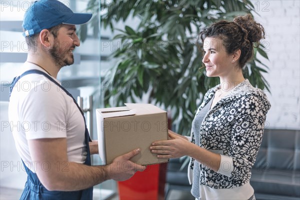 Side view woman taking parcel from deliveryman