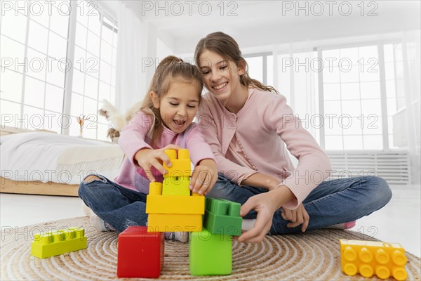 Front view two sisters playing home toys