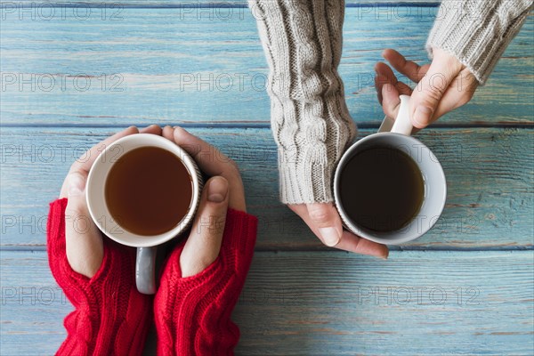 Hands holding cups tea