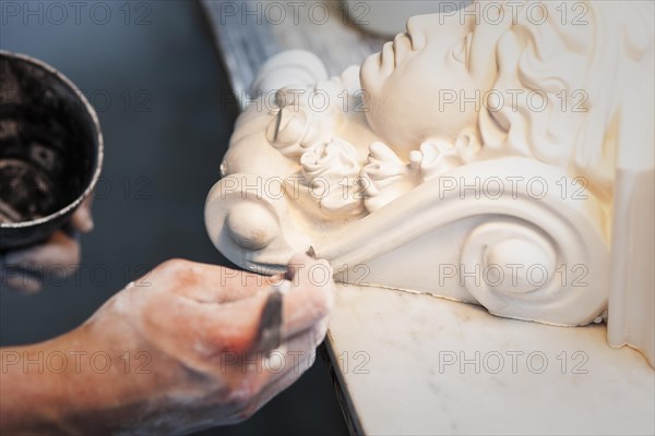 A plasterer restores a stucco figure