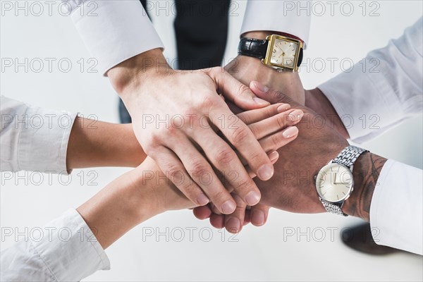 People putting stacked hands together promising help support against white backdrop