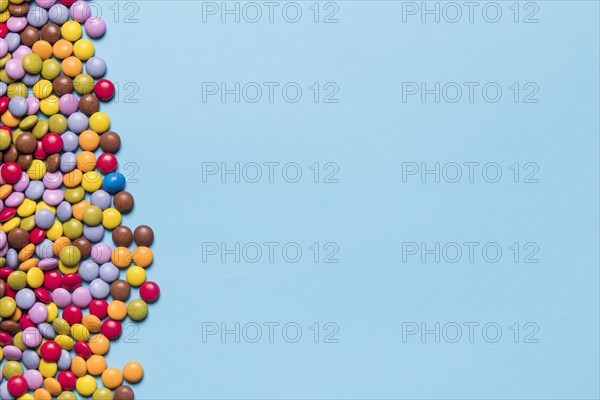 Colorful gem candies side blue background