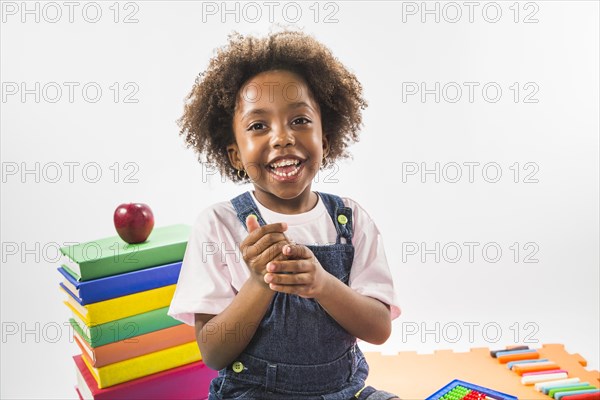 Kid sitting books smiling studio