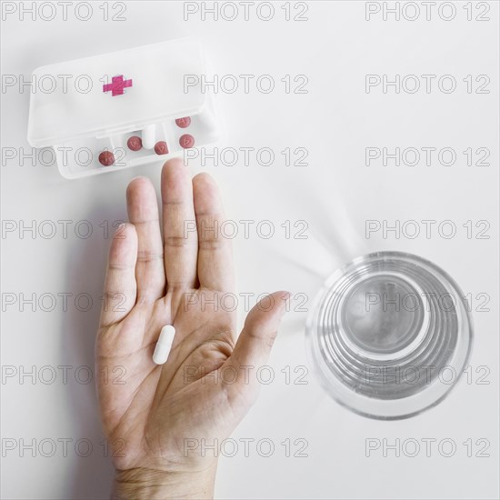 Person s hand taking tablet from pill organizer box white background