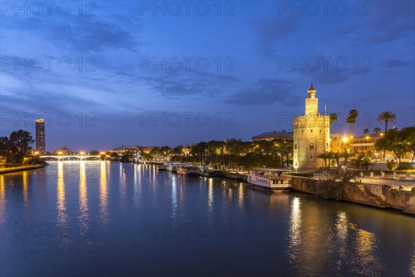 On the banks of the Guadalquivir River with the historic Torre del Oro tower at dusk