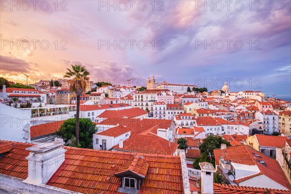 View of Lisbon famous view from Miradouro de Santa Luzia tourist viewpoint over Alfama old city district on sunset with dramatic overcast sky. Lisbon